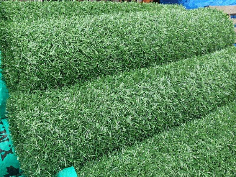 Rolls of green artificial grass fence made in Turkey, stacked ready for export